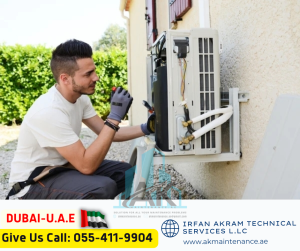 An image of a person holding a phone and looking at it while standing next to an air conditioning unit